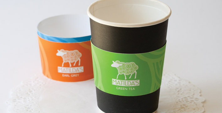 Disposable paper cups with black paper that contrasts with the white interior paper. A colour coded band both identifies which tea a customer has ordered as well as protects hands from the hot contents.