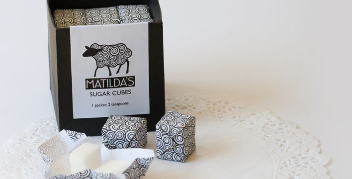Sugar cubes that are wrapped in paper featuring the Matilda's scroll pattern.
