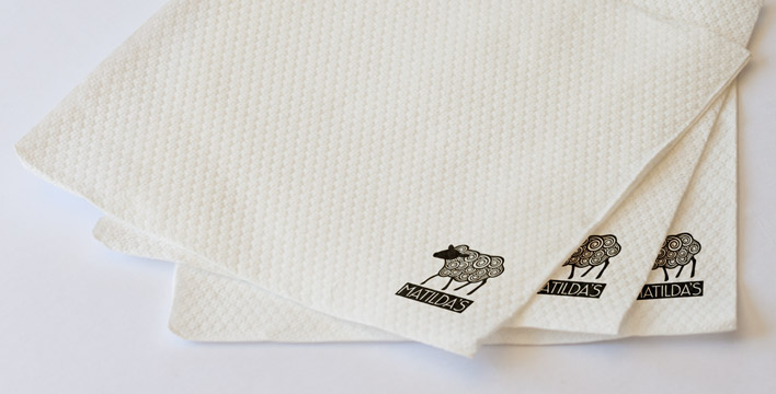 White textured napkins that feature the Matilda's logo in the bottom-right corner.